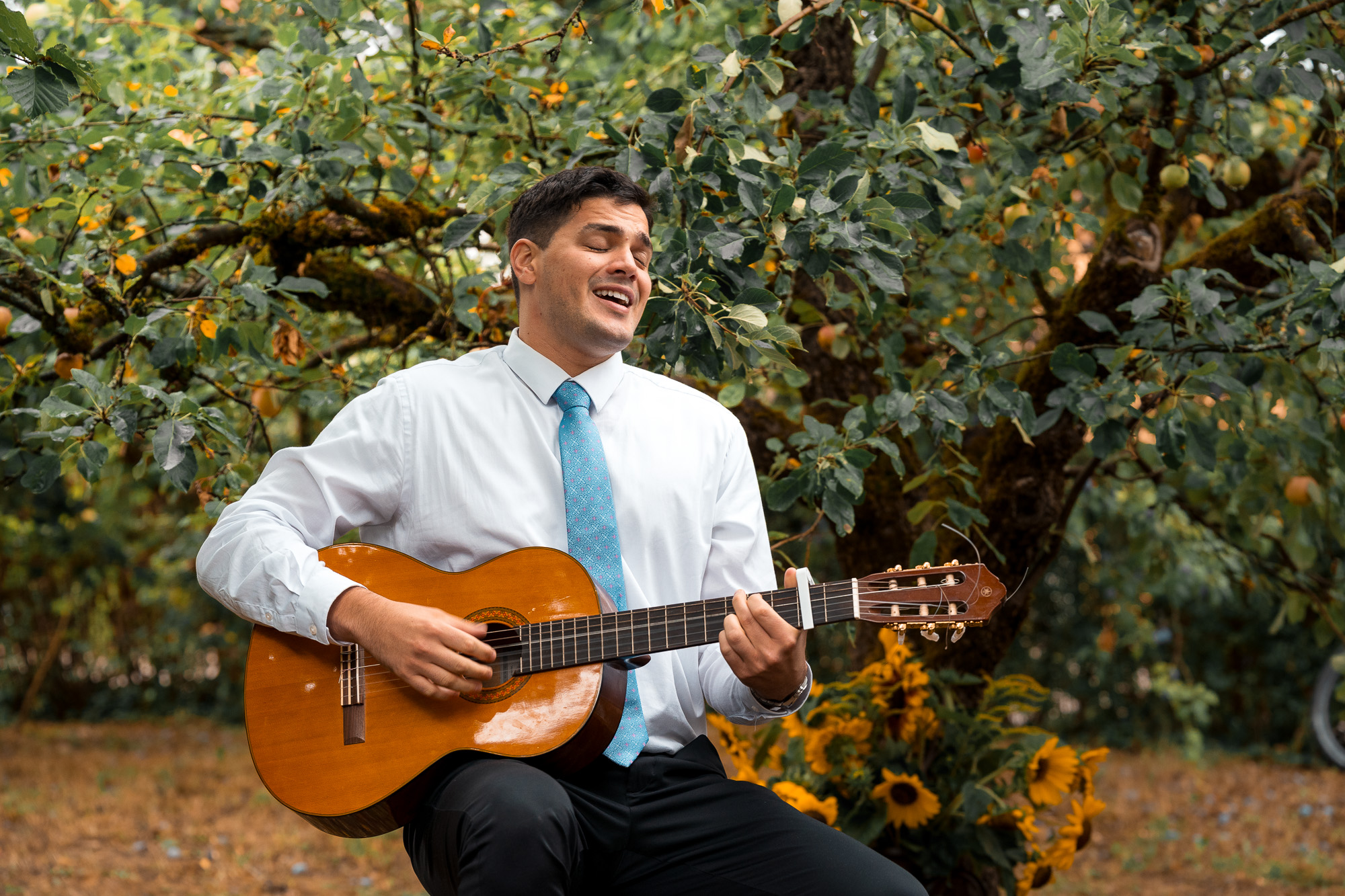 Ein Gast spielt Gitarre und singt für das Brautpaar bei der Hochzeitsfeier im Garten
